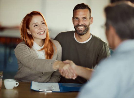 Young happy couple came to a successful agreement with their agent during a meeting in the office.